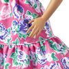 Poupée ​Barbie Fashionistas 150 chauve, vêtue d'une robe rose florale, de bottillons blancs et de boucles d'oreilles